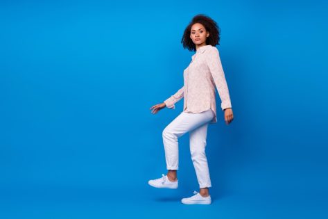 Woman wear pink shirt walking up stairs on blu background.