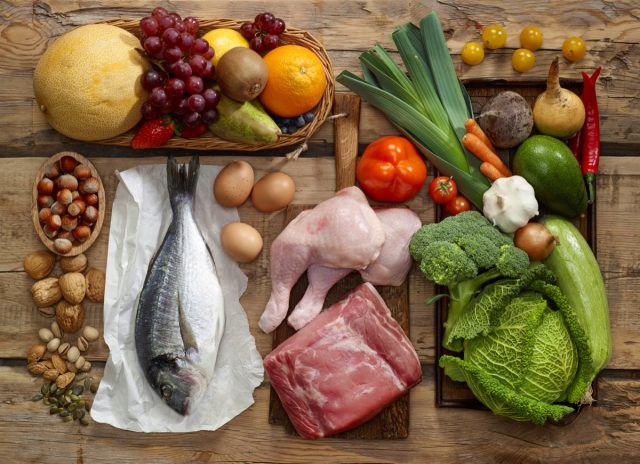 Various Paleo diet products on wooden table, top view.