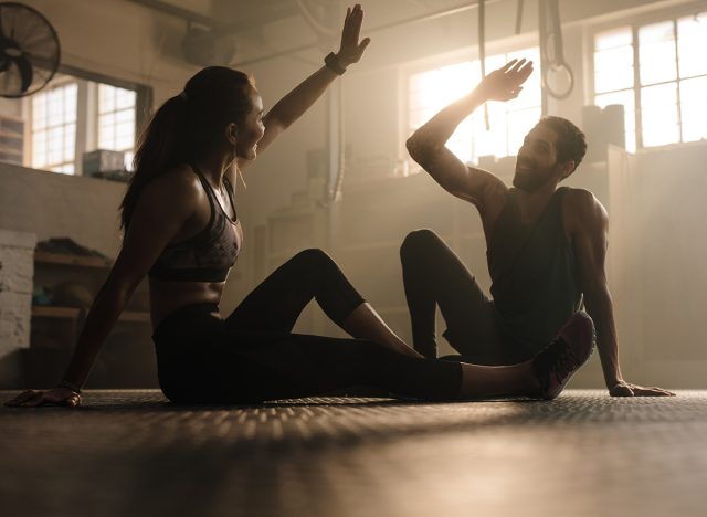 Fitness man and woman giving each other a high five after the training session in gym. Fit couple high five after workout in health club.