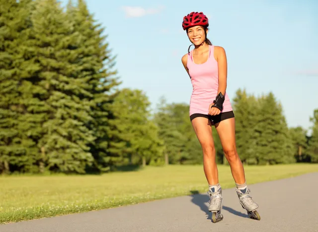 Roller skating girl in park rollerblading on inline skates. Mixed race Asian Chinese / Caucasian woman in outdoor activities.