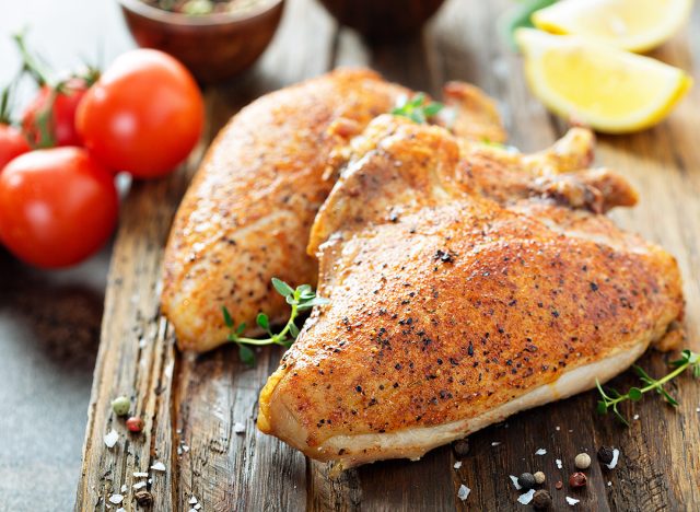 Grilled or smoked chicken breast with bone and skin on a cutting board