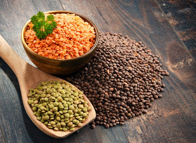 Composition with bowl of lentils on wooden table.