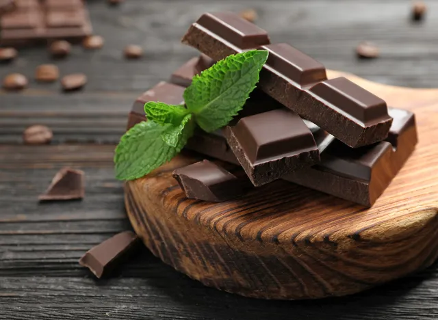 Pieces of dark chocolate with mint on wooden table