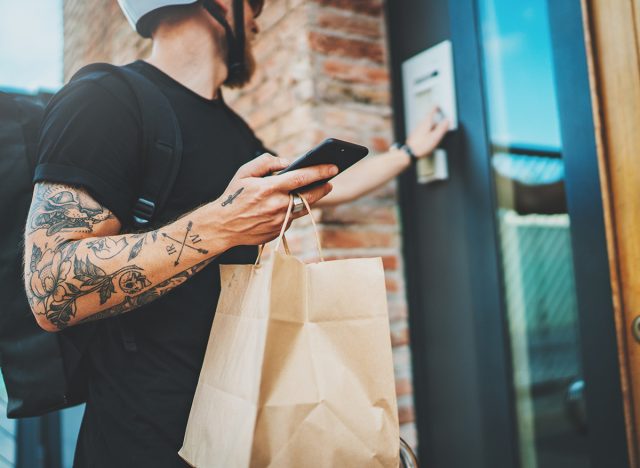 Courier delivery food service at home. Man courier delivered the order no name bag with food.