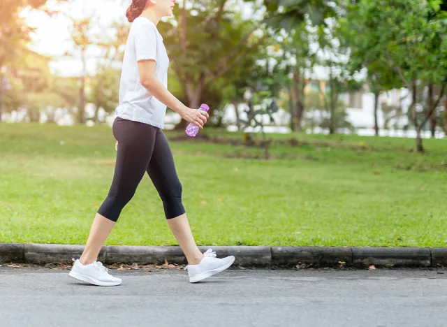 Woman walking in the park with bottle water in summer health care concept.