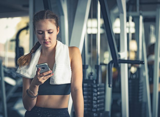 Happy Young attractive women fitness using smartphone resting in gym during morning exercise. Relaxation after hard workout in gym. Healthy sports lifestyle, Fitness concept.