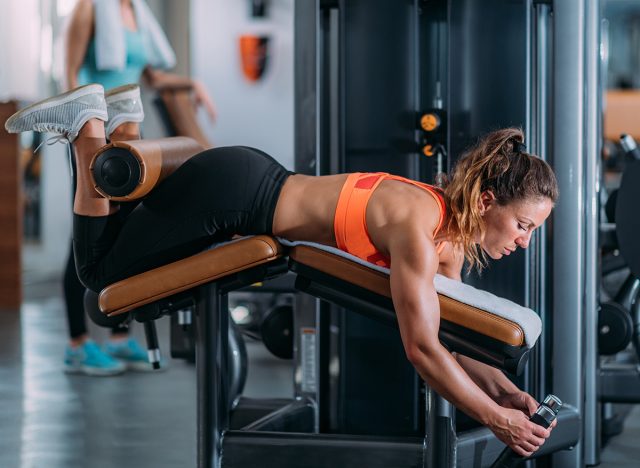 Female Athlete Exercising at Lying Leg Curl Bench in The Gym