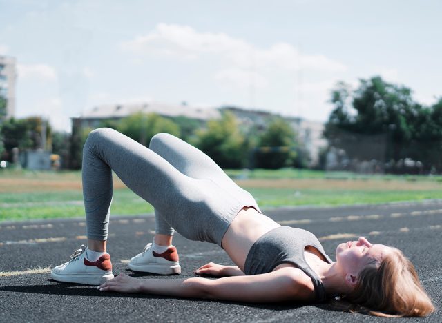 Fitness woman doing hip workout exercise on a stadium. fitness girl in sportswear exercising, doing pelvic muscle exercises