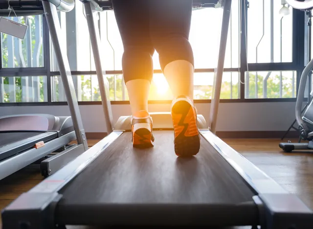 leg of fat woman being run or jog on belt of treadmill machine