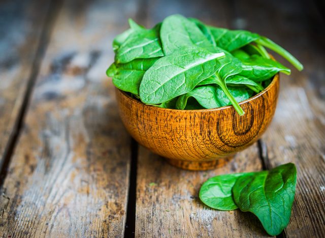 Fresh spinach in a bowl on rustic wooden background