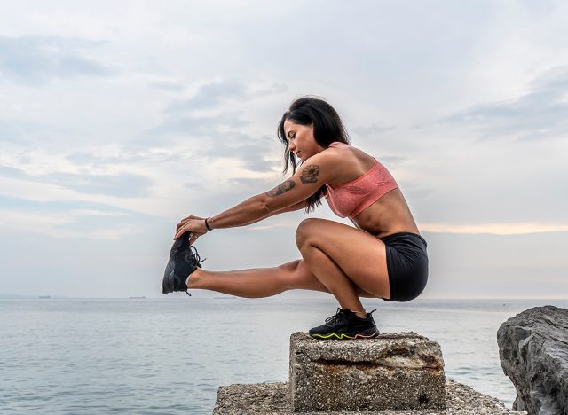 Fitness woman doing pistol squat outdoors.