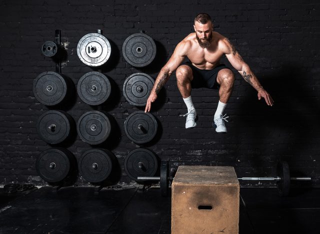 Young dedicated serious active strong fit sweaty muscular man with big muscles doing box jump workout in the gym as hardcore cross training real people motivation sport exercise