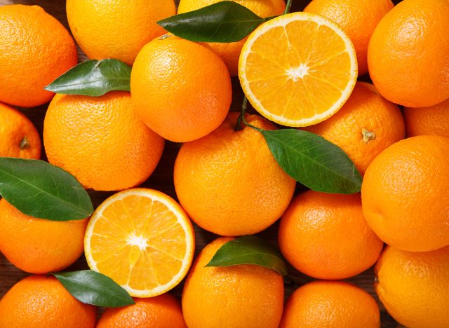 fresh orange fruits with leaves as background, top view