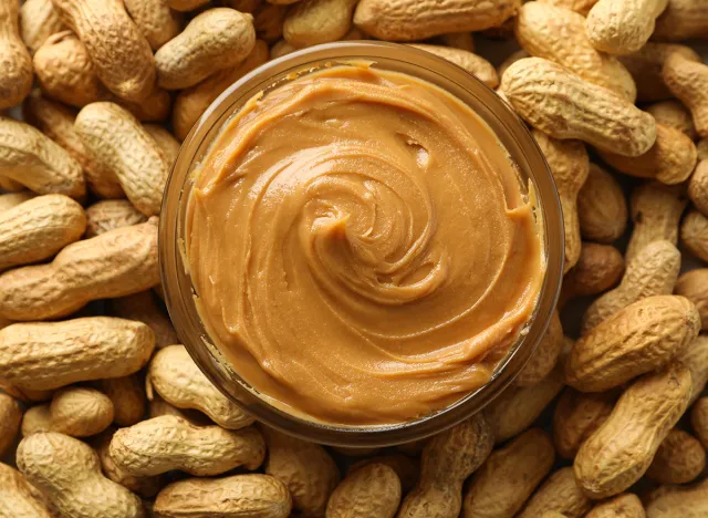 Jar with peanut butter on peanut background, close up