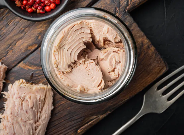 Canned tuna fillet meat in olive oil, on black background, flat lay