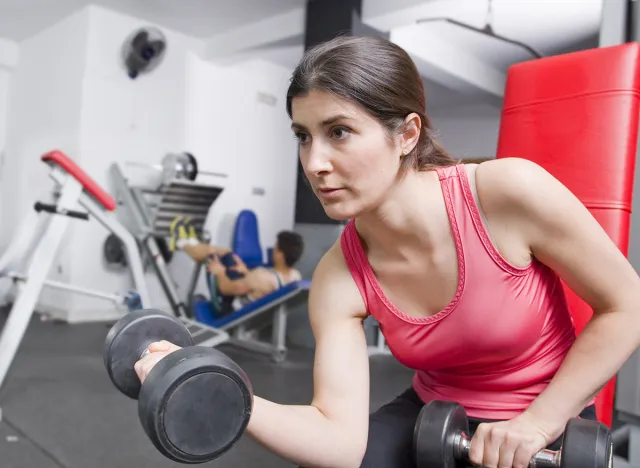 Woman training in gym room ready for fitness biceps exercises
