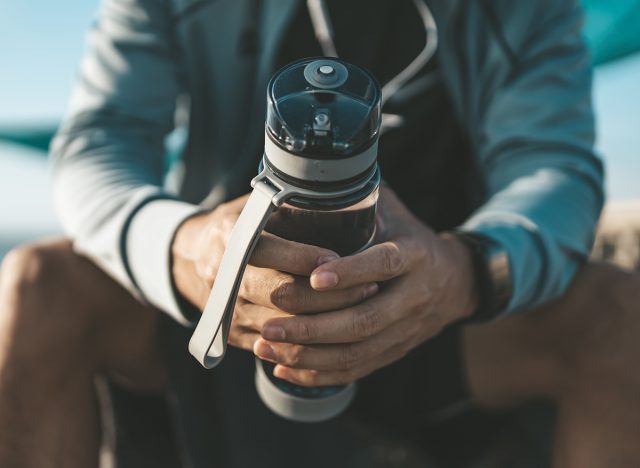 sport man sitting after running and holding water bottle drink. Sport thirsty and resting after exercise.