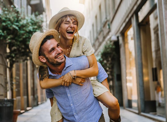 Couple of tourists having fun walking on city street at holiday - Happy friends laughing together on vacation - People and holidays concept