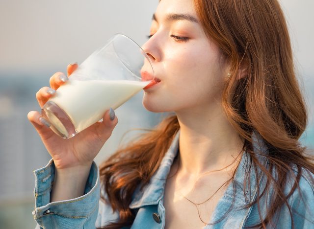 Attractive Asian woman drinking milk and smiling at home close up face.healthy life style outdoor city roof top.