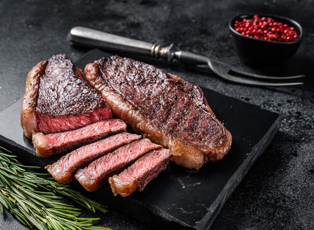 Grilled top sirloin or cup rump beef meat steak on marble board. Black background. Top view