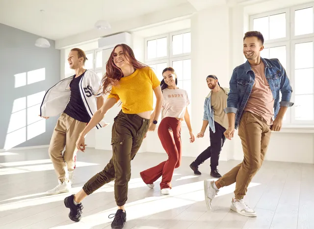 Group of happy beautiful young people enjoying a contemporary dancing class. Team of cheerful smiling dancers in casual wear practising a new choreo and having a good time together in a modern studio