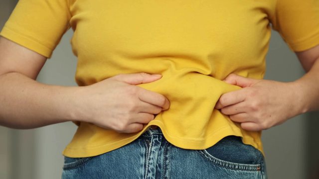 Woman body fat belly. Obese Woman with fat upset about her belly. Fat woman with tight clothing worried about weight diet lifestyle concept.
