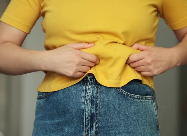 Woman body fat belly. Obese Woman with fat upset about her belly. Fat woman with tight clothing worried about weight diet lifestyle concept.