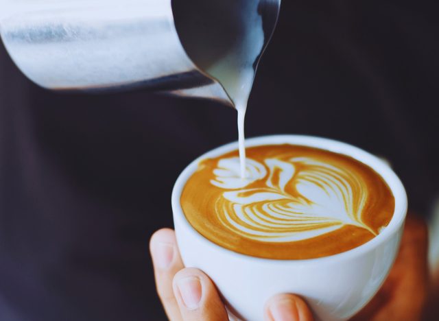 a man person making latte art in a cup of coffee.
