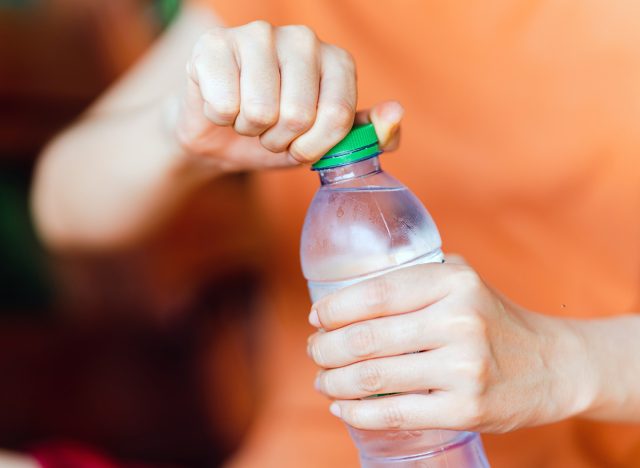 Women holding drinking bottle and opening the cap of a water bottle to drink water.