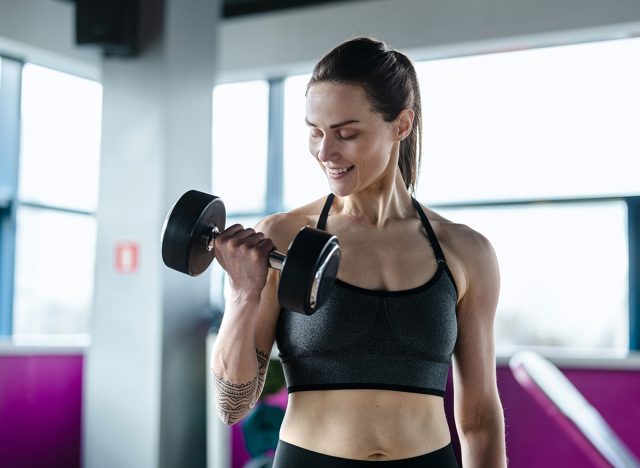 Young woman exercising with dumbbells in a health club