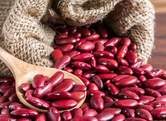 close-up red kidney bean in wood spoon and gunny bag on wood tab