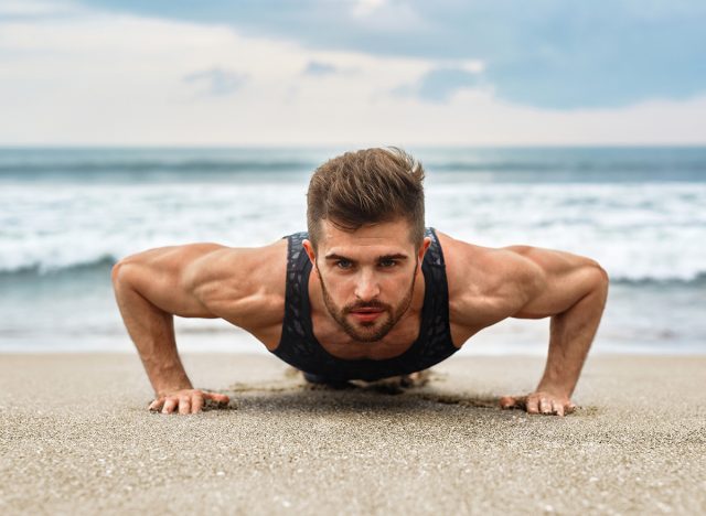 Workout Exercise. Closeup Of Healthy Handsome Active Man With Fit Muscular Body Doing Push Ups Exercises. Sporty Athletic Male Exercising At Beach, Training Outdoor. Sports And Fitness Concept