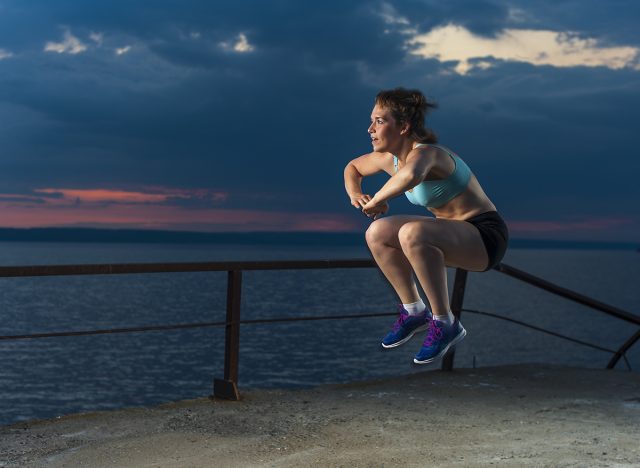 Young caucasian woman in sportswear doing plyometric exercises on pier. Fitness workout outdoors