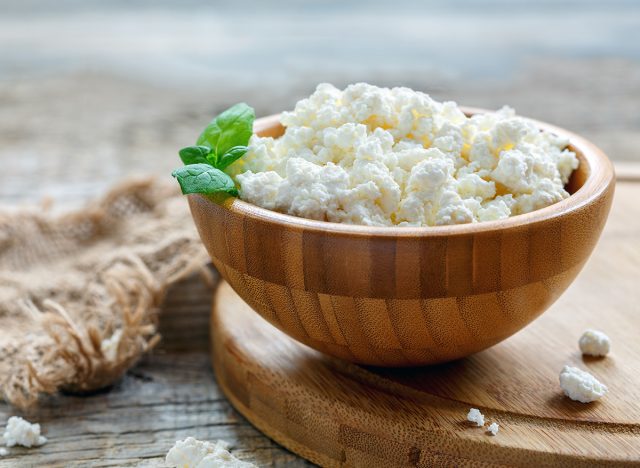 Cottage cheese and mint in a wooden bowl on an old rustic table, selective focus.