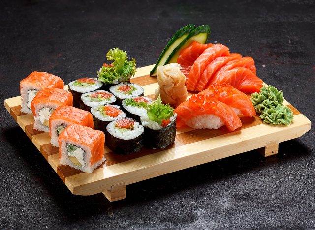 Japanese cuisine. Sushi set on a wooden plate over dark stone background.