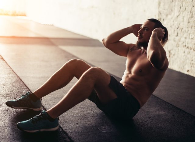 Muscular man exercising doing sit up exercise. Athlete with six pack, white male, no shirt