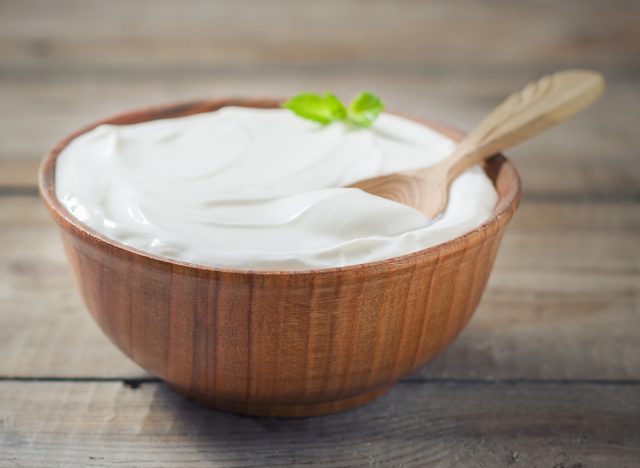 Greek yogurt in a wooden bowl on a rustic wooden table. Selective focus