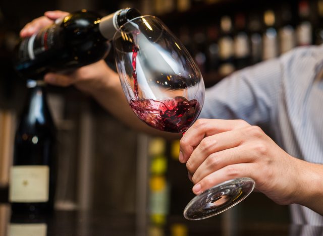 Waiter pouring red wine in a glass.