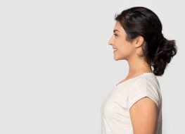 Side profile view smiling happy millennial Indian ethnicity girl standing on right, looking at empty space.