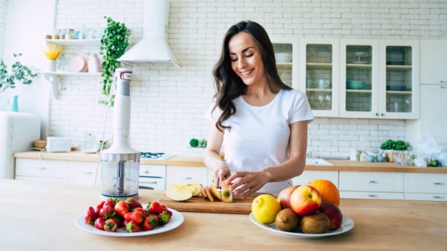 Woman making fruits smoothies with blender