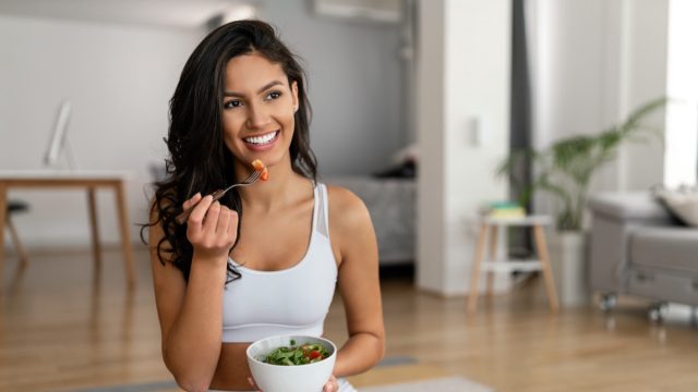 Young woman eating a healthy salad after workout.