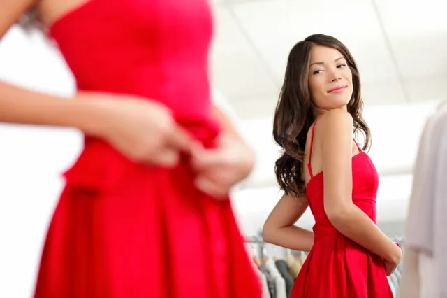 Woman trying dress in looking in mirror cheerful and happy.