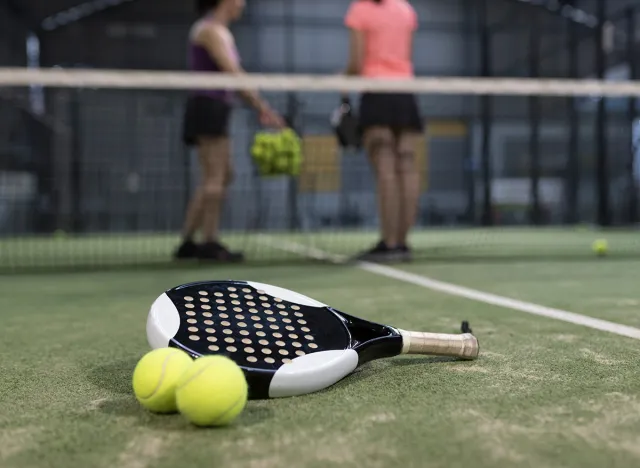 Paddle tennis objects on turf ready for tournament and women in background