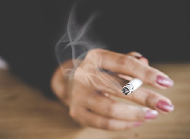 closeup woman hand smoking cigarette ,unhealthy lifestyle concept