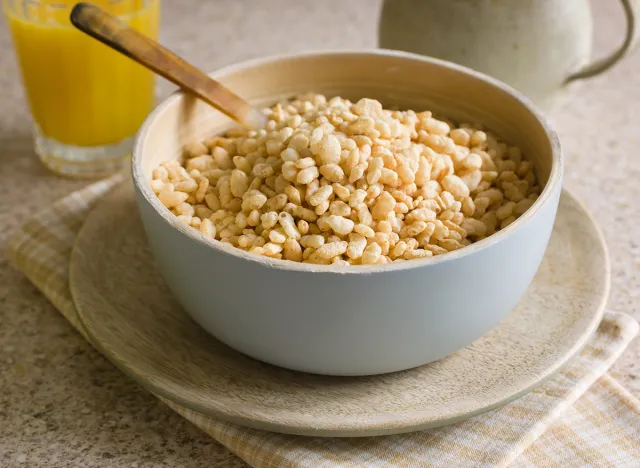 Puffed rice breakfast cereal in a wooden bowl with juice and a milk jug