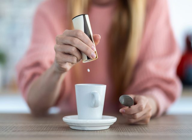 Close-up of woman hand throwing saccharin pills on coffee cup in the kitchen at home.