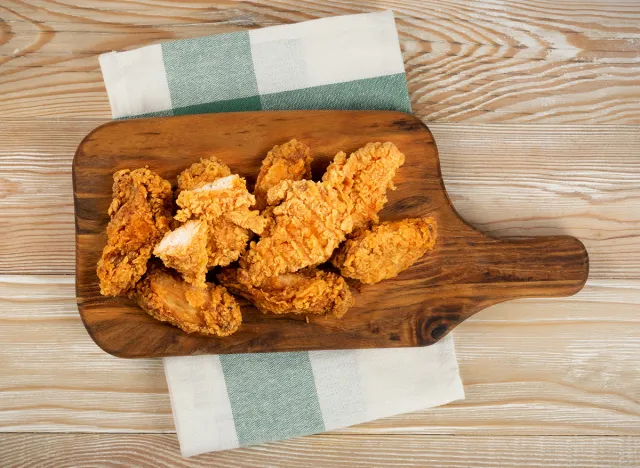 Breaded Fried Chicken Wings, Fingers and Drumsticks on Wooden Rustic Background Top View. Hot Crispy Chicken Nuggets, Fillet Strips, Meat Pieces in Breadcrumbs