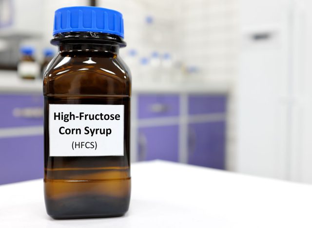 Selective focus of high-fructose corn syrup or hfcs food and beverage sweetener in dark brown glass bottle inside a laboratory.