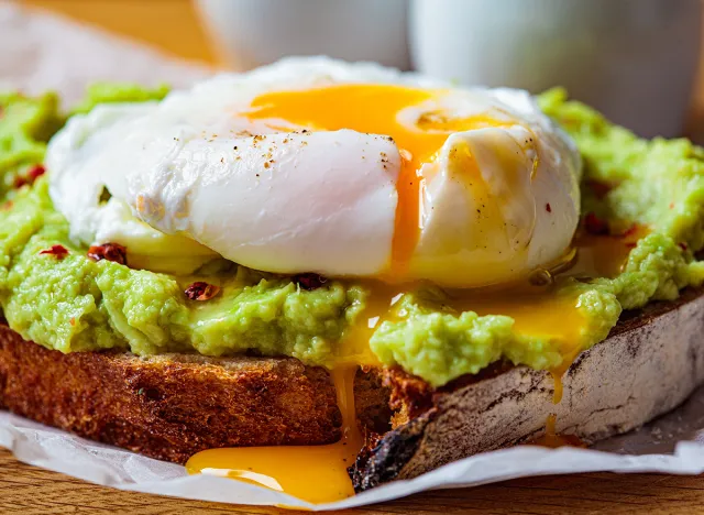 Avocado toast with poached egg on a wooden board. Breakfast concept.