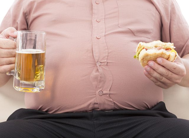 fat business man holding beer mug and hamburger